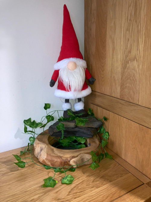 a gonk stands proudly on some rocks, surrounded by fake ivy